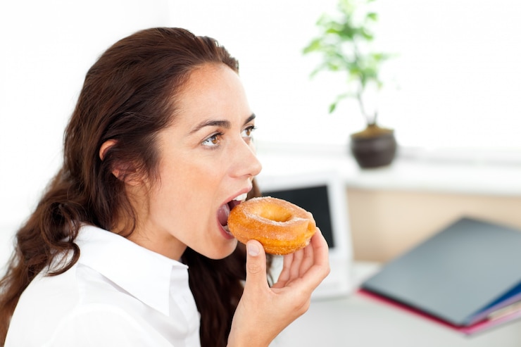 Foto linda empresária hispânica comendo uma rosquinha