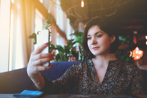 Linda empresária no restaurante chama seu smartphone Morena bonita em um café