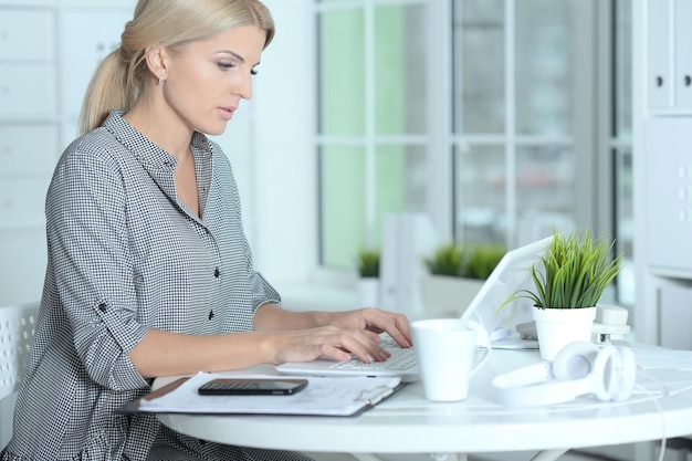 Linda empresária sorridente trabalhando com laptop em casa