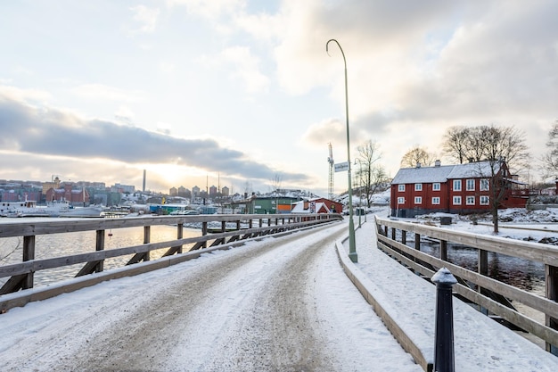 Linda estrada de neve cercada por edifícios sob o céu nublado e brilhante em Estocolmo, Suécia