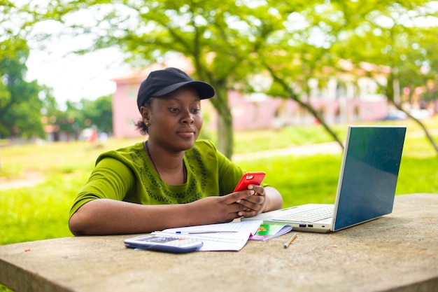 Linda estudante africana estudante universitária usando laptop ao ar livre