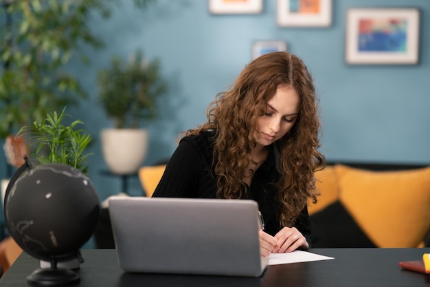 Linda estudante está estudando remotamente em casa, mulher está usando sites de navegação de laptop