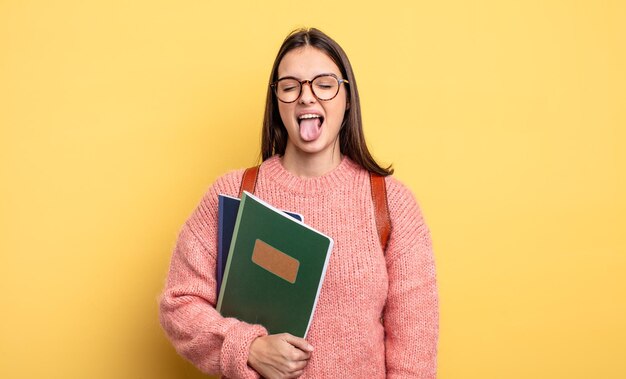 Linda estudiante con actitud alegre y rebelde, bromeando y sacando la lengua