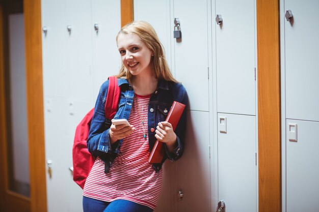 Linda estudiante con mochila apoyado contra el armario