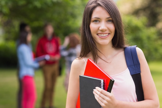 Linda estudiante sonriendo a la cámara afuera en el campus