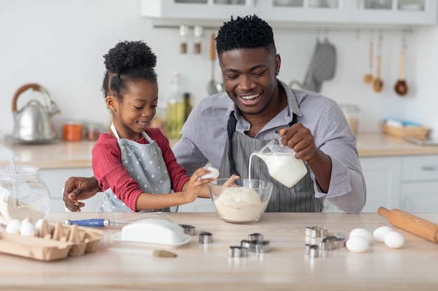 Linda família afro-americana fazendo massa para o interior da cozinha de biscoitos