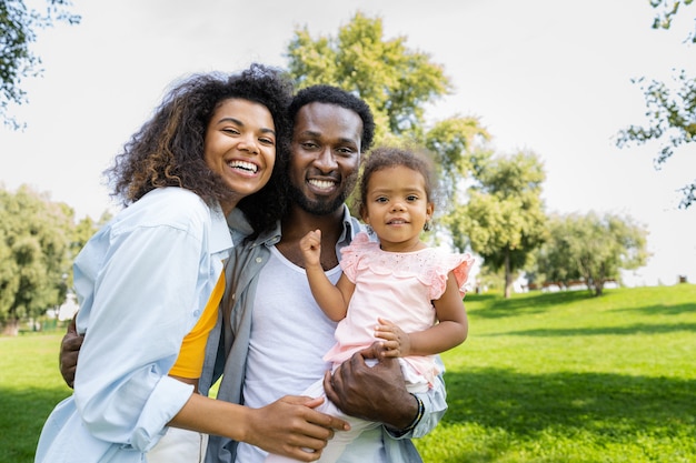 Linda família afro-americana feliz se unindo no parque - família negra se divertindo ao ar livre