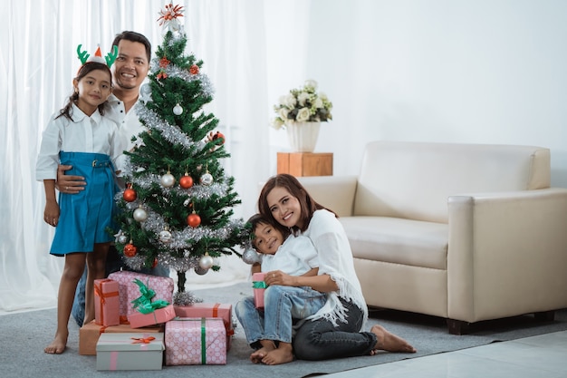 Linda família asiática com árvore de Natal na sala de estar