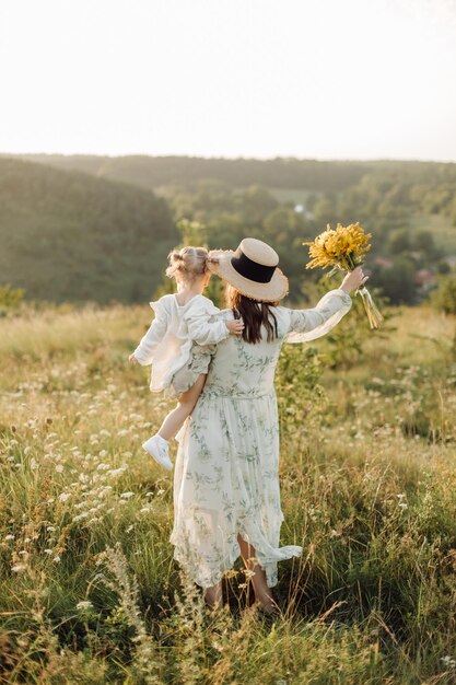 Linda família caucasiana de pai mãe e filha posando na câmera no fundo do campo verde