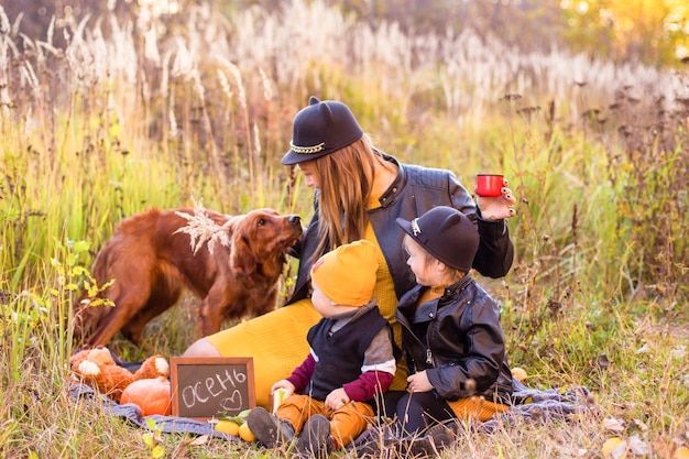 Linda família com um cachorro golden retriever em uma caminhada na natureza ensolarada de outono