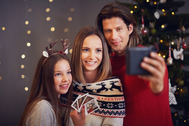 Linda família comemorando o natal em casa e tirando fotos instantâneas