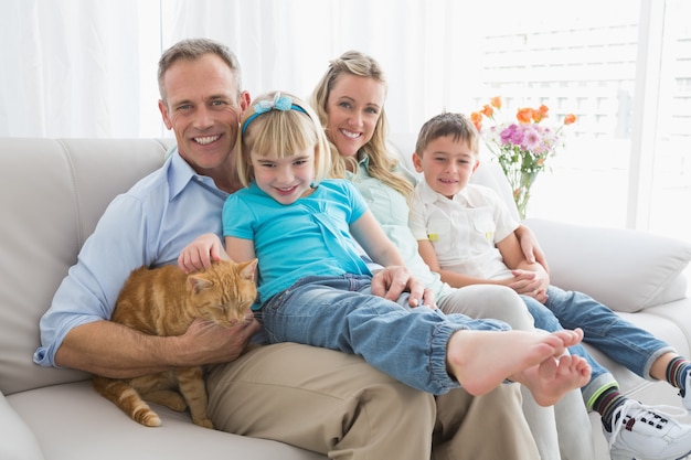 Linda familia descansando juntos en el sofá con su gato