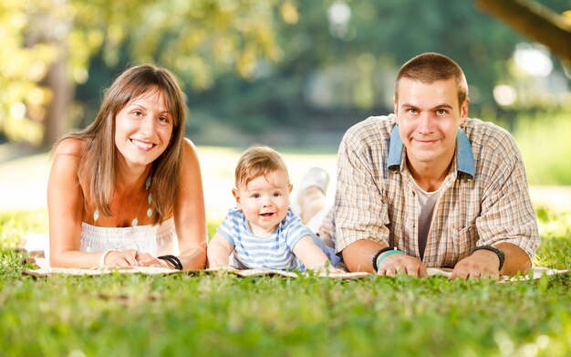 Linda família feliz deitada na grama no parque