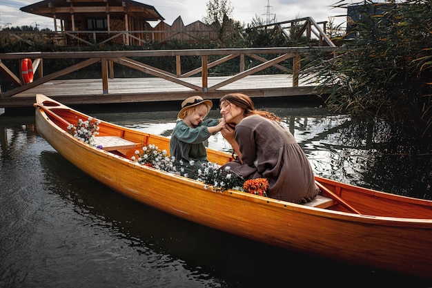 Linda família feliz mãe e filha em um barco de madeira no lago juntas