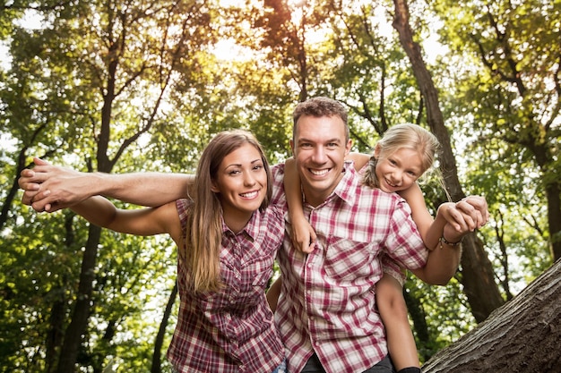 Linda família jovem desfrutando de uma carona na floresta.