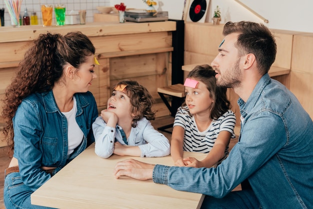 Foto linda família jovem jogando adesivo de adivinhação no café