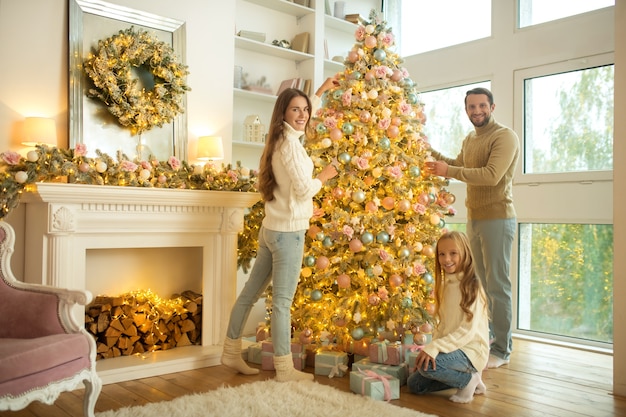 Linda familia joven decorar el árbol de Navidad en casa