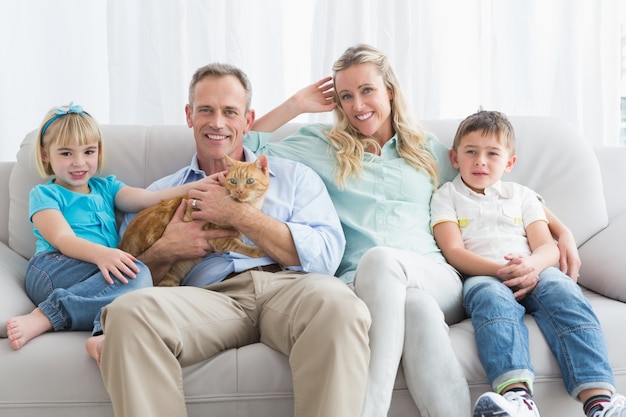 Linda familia relajarse juntos en el sofá con su gato