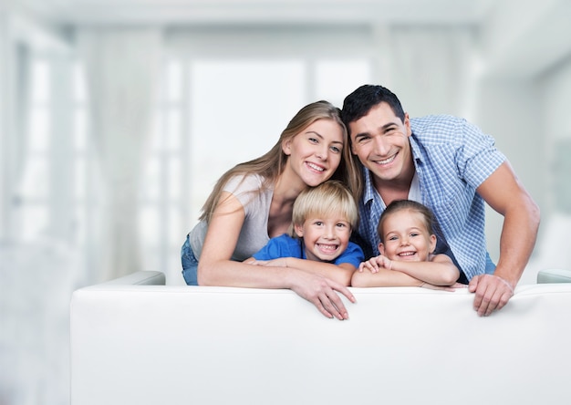 Linda família sorridente na sala no sofá