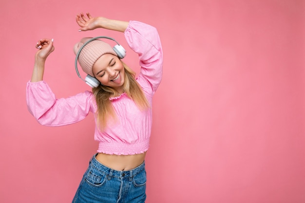 Linda feliz sorridente jovem loira vestindo blusa rosa e chapéu rosa isolado sobre rosa