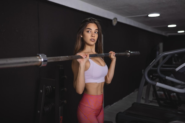 Linda, forte, sexy, musculosa, jovem, caucasiana, em forma, mulher treinando na academia com dieta, aumentando os músculos e posando de cuidados de saúde de musculação e conceito de barra de corpo de fitness