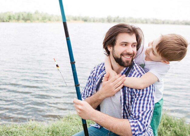 Linda foto de papá barbudo y su pequeño hijo pasar tiempo juntos. Niño está abrazando a su padre mientras el hombre está sonriendo y mirando a su hijo. Son felices.