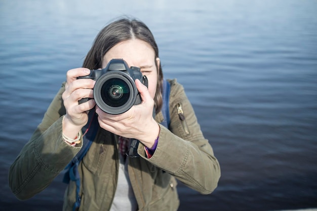 Linda fotógrafa con cámara en las manos en el fondo del río