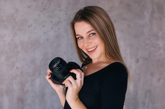 Linda fotógrafa feminina sorrindo e posando com câmera dsl