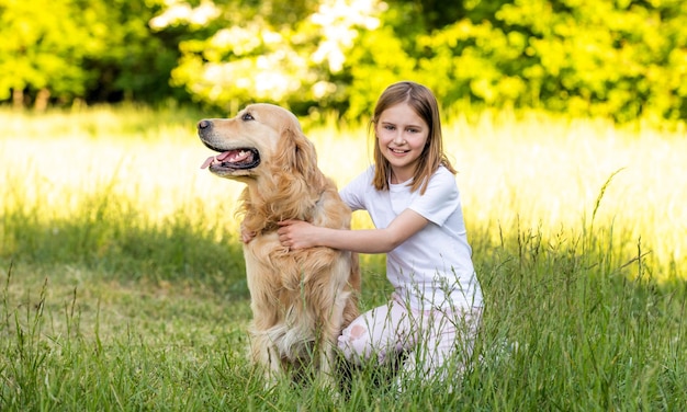 Linda garota abraçando com adorável cachorro golden retriever ao ar livre