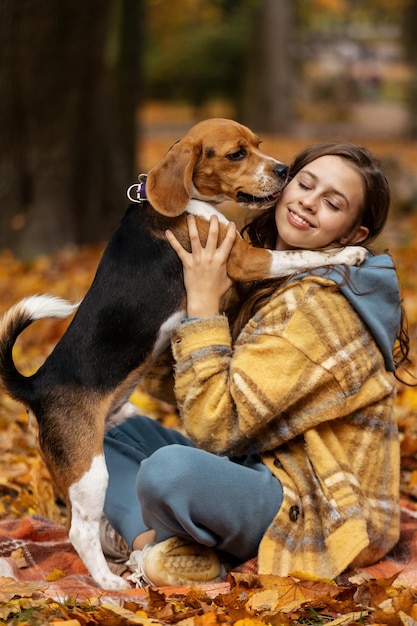 Linda garota abraçando com cachorro beagle no parque outono.