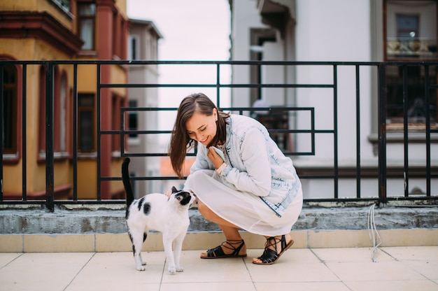 Linda garota acariciando um gato de rua na rua e sorrindo