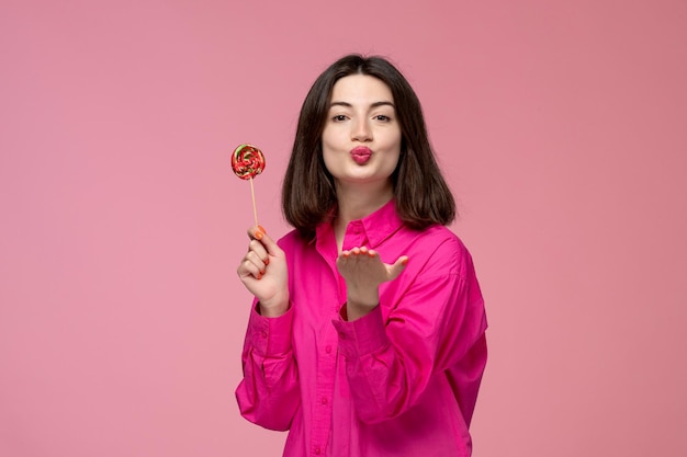 Linda garota adorável adorável linda senhora de camisa rosa mandando beijos com pirulito