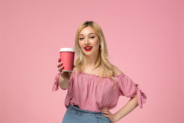 Linda garota adorável jovem com batom vermelho na blusa rosa dando copo de papel rosa