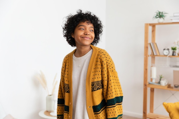 Linda garota afro-americana com penteado afro sorrindo em casa jovem africana com