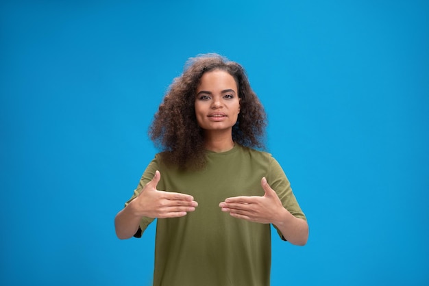 Linda garota afro-americana dizendo olá usando as mãos para se comunicar jovem de cabelos cacheados sh ...