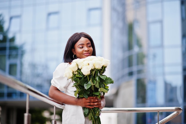 Linda garota afro-americana segurando buquê de flores de rosas brancas em namoro na cidade Empresária negra com buquê de flores