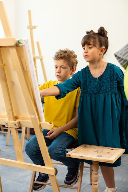 Linda garota ajudando seu colega a pintar na escola de arte