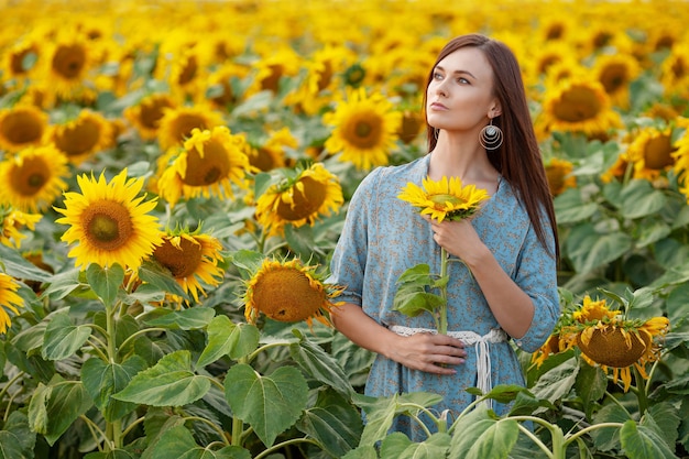 Linda garota alegre curtindo a natureza no campo de girassóis