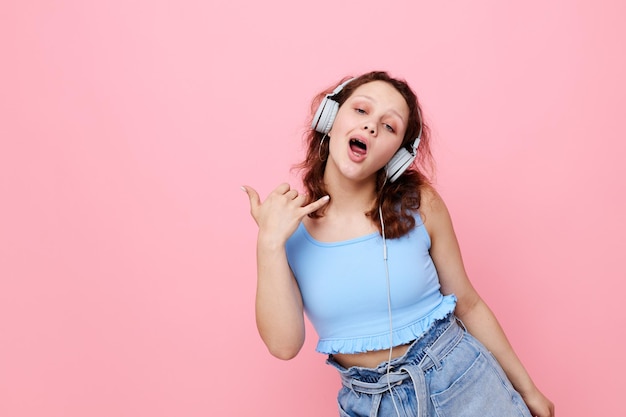 Linda garota alegre usando fones de ouvido entretenimento de moda posando inalterado