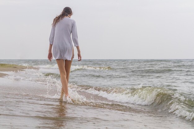 Linda garota andando à beira-mar em camisa branca e pernas nuas mar negro zatoka odesa ucrânia