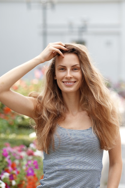 Linda garota andando ao longo do jardim de flor. Feliz turista com vento no cabelo dela.