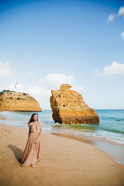 Linda garota andando na praia ao pôr do sol, conceito de liberdade