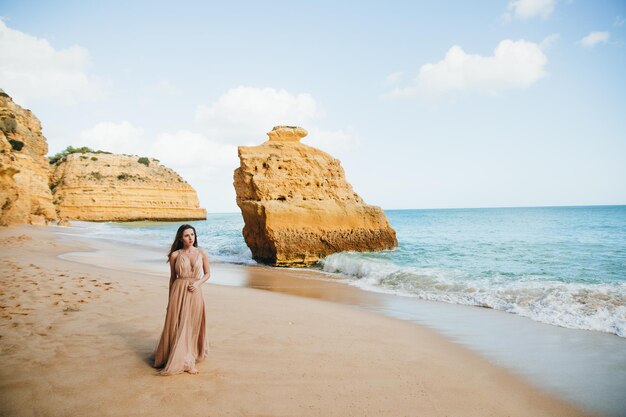 Linda garota andando na praia ao pôr do sol, conceito de liberdade