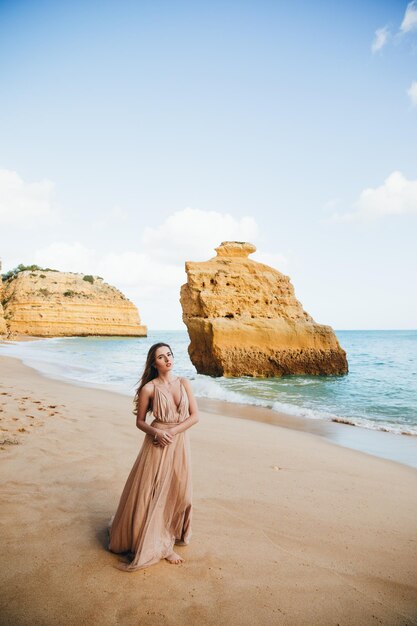 Linda garota andando na praia ao pôr do sol, conceito de liberdade