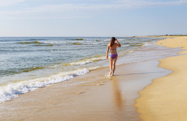 Linda garota andando na praia de verão