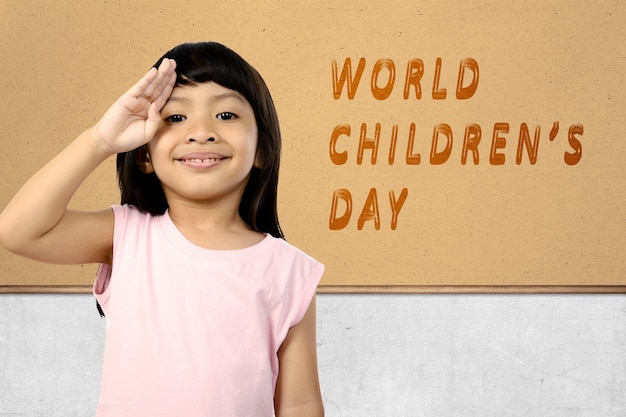 Foto linda garota asiática com uma expressão engraçada em pé com o texto do dia mundial da criança na parede. dia mundial da criança