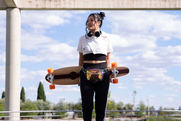 Linda garota asiática em um parque com um skate