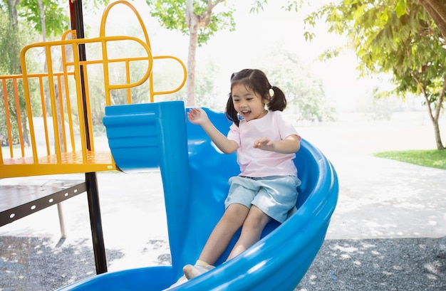 Linda garota asiática sorri brincar na escola ou jardim de infância ou playground Atividade saudável de verão para crianças Menina asiática escalando ao ar livre no playground Criança brincando no playground ao ar livre