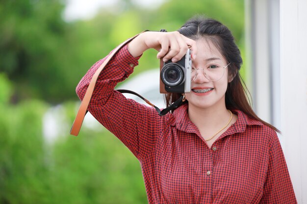 Linda garota asiática tailandesa adolescente com câmera digital para fotógrafo amador.