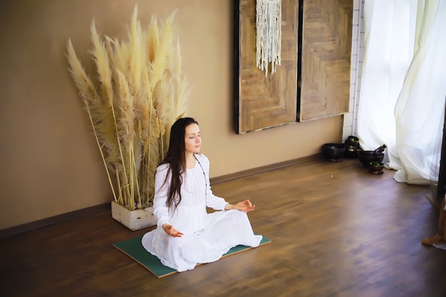 Foto linda garota atlética fazendo exercícios de ioga desfrutar de meditação em casa. sem estresse, hábito saudável, conceito de alívio da ansiedade. pose de lótus.